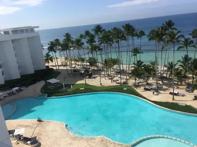 a view of the pool and beach from the balcony of a resort at Marbella Juan Dolio in Juan Dolio