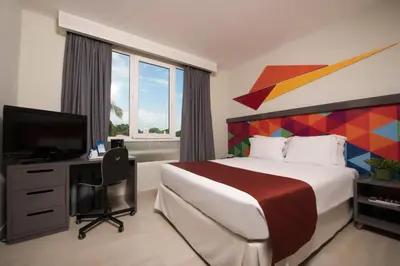 a hotel room with a bed and a television at Novus Plaza Hodelpa in Santo Domingo