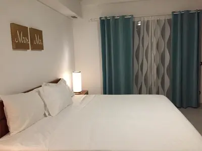 a bedroom with a large white bed with blue curtains at Aligio Beachfront Paradise in Las Terrenas