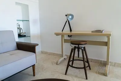a desk and a stool next to a table and a chair at 3BR / 3BA Modern Paradise Loft Condo in Gated Community w/ Daily Housekeeping in Sosúa