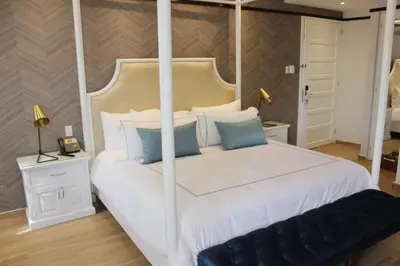 a bedroom with a large white bed with blue pillows at Hotel Conde de Penalba in Santo Domingo