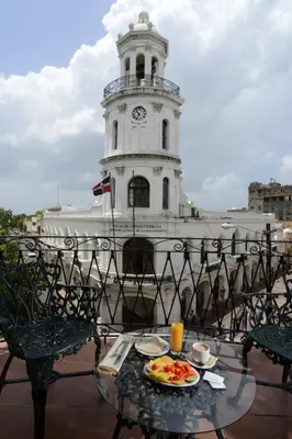 a table with a plate of food in front of a clock tower at Hotel Conde de Penalba in Santo Domingo