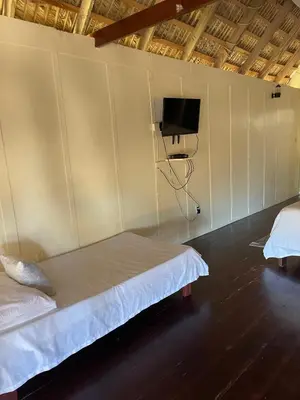 a room with two beds and a tv on the wall at Playa Paraiso en Magante in La Yagua