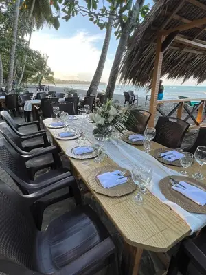 a long table with glasses and napkins on a beach at Playa Paraiso en Magante in La Yagua