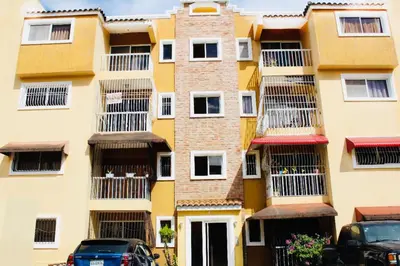 a building with balconies and cars parked in front of it at Apartamento Los Rieles in Santiago de los Caballeros