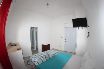 a small bedroom with a bed and a television at Caribbean Hotel Santo Domingo in Santo Domingo