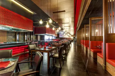 a restaurant with wooden tables and red seats at Royalton Bavaro, An Autograph Collection All-Inclusive Resort & Casino in Punta Cana