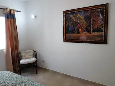 a painting on the wall of a bedroom with a chair at Luxury apartment with ocean view at the beach in Cabarete