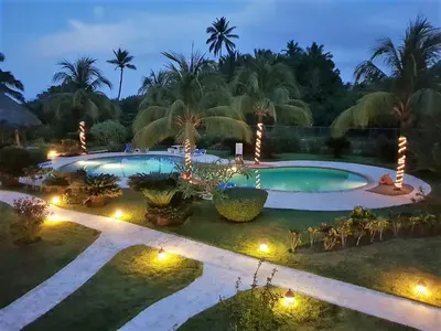 a backyard with a swimming pool at night with lights at Luxury apartment with ocean view at the beach in Cabarete