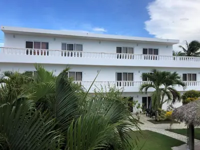 a white building with palm trees in front of it at Diamond Hotel Cabarete in Cabarete