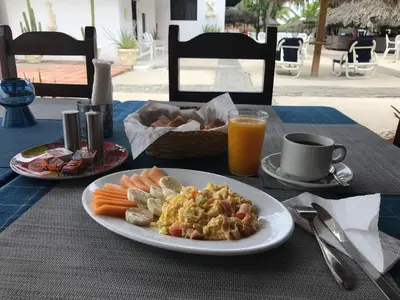 a table with a plate of food and a cup of orange juice at Hotel Zapata in Boca Chica