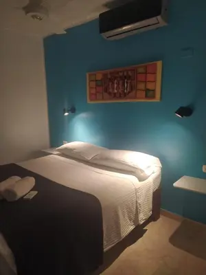 a bedroom with a bed with a blue wall at Hotel Pedernales Italia Republica Dominicana in Pedernales