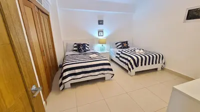 two twin beds in a room with a door at Las Olas by Destinos1a in Juan Dolio