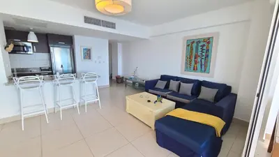 a living room with a blue couch and a kitchen at Las Olas by Destinos1a in Juan Dolio