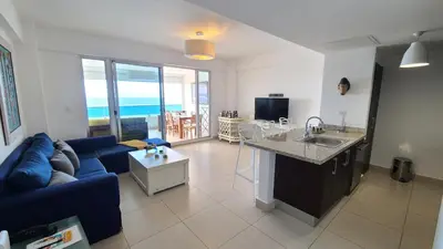 a living room with a blue couch and a kitchen at Las Olas by Destinos1a in Juan Dolio