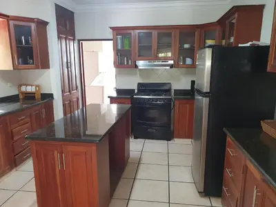 a kitchen with wooden cabinets and a black refrigerator at Villa M-6 Metro Country Club in Juan Dolio