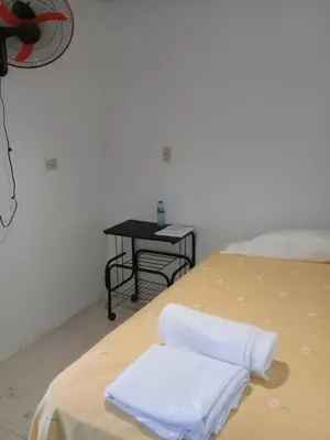 a bed with two white towels on it with a table at Hostel Quintonido in Jarabacoa