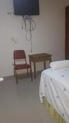 a room with a tv and a chair and a table at Hostel Quintonido in Jarabacoa