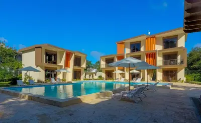 a swimming pool with chairs and umbrellas in front of a building at Caribbean Diamond Boutique Hotel in Sosúa