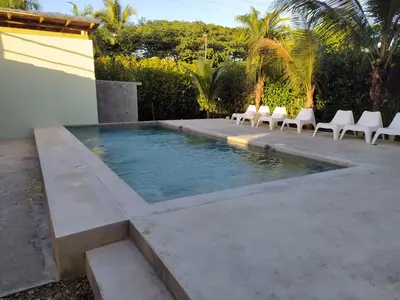 a swimming pool with white chairs next to a house at Residencia El Balatà in Las Terrenas