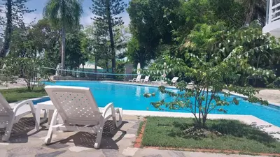 a swimming pool with two chairs and a tree at Tropical Casa Laguna in Cabarete