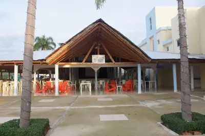 a building with orange tables and chairs in a parking lot at Gran Hotel Marien in Sabaneta