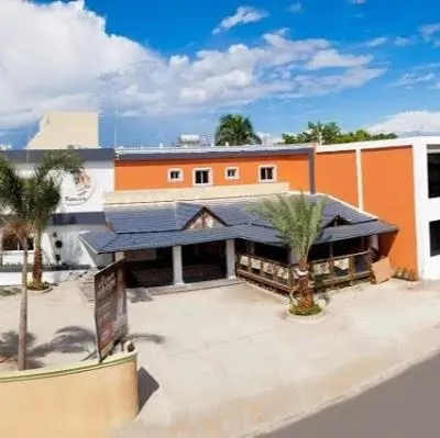 an orange and white building with palm trees in front of it at Gran Hotel Marien in Sabaneta