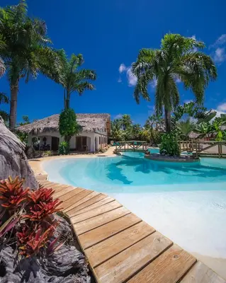 a swimming pool with a wooden walkway and palm trees at Paradiso del Caribe in Las Galeras