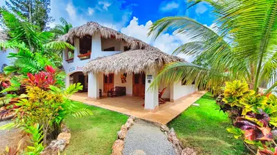 a villa with a thatched roof and a yard at Paradiso del Caribe in Las Galeras