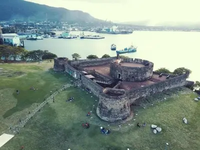 an old stone building next to a body of water at Hotel Kevin in San Felipe de Puerto Plata