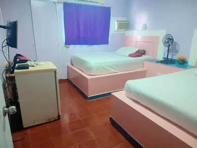 a bedroom with two beds and a purple curtain at Hotel Kevin in San Felipe de Puerto Plata