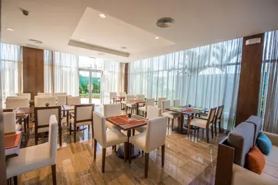 a dining room with tables and chairs and windows at Hampton By Hilton Santo Domingo Airport in Boca Chica