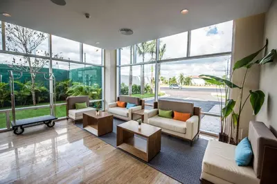 a living room with furniture and a large window at Hampton By Hilton Santo Domingo Airport in Boca Chica