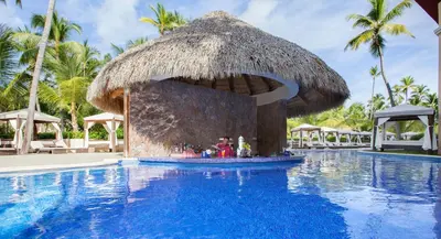 a resort with a swimming pool with a straw hut at Majestic Colonial Punta Cana - All Inclusive in Punta Cana