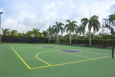 a tennis court with palm trees and a basketball hoop at Majestic Colonial Punta Cana - All Inclusive in Punta Cana