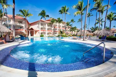 a large swimming pool with palm trees and a hotel at Majestic Elegance Punta Cana - All Inclusive in Punta Cana