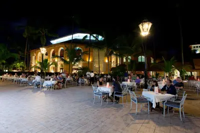 a group of people sitting at tables in front of a building at Majestic Elegance Punta Cana - All Inclusive in Punta Cana