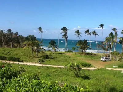 a van parked on a dirt road next to the ocean at Villa La Caleta in Las Galeras