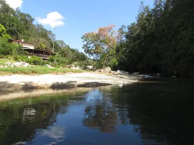 a river with trees and a house in the background at Arroyo Frío River Lodge in Arroyo Frío