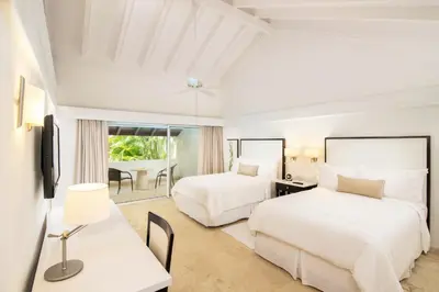 a hotel room with two beds and a desk at Casa de Campo Resort & Villas in La Romana
