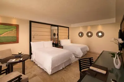 a hotel room with two beds and a table at Casa de Campo Resort & Villas in La Romana