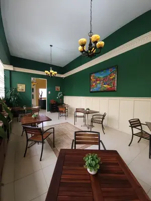 a restaurant with green walls and tables and chairs at Hotel Class Colonial in Santo Domingo
