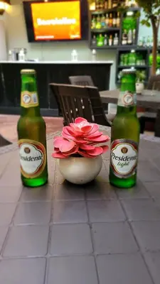 two bottles of beer on a table with a flower in a bowl at Hotel Class Colonial in Santo Domingo