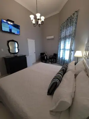 a bedroom with a large bed with a television on the wall at Hotel Class Colonial in Santo Domingo