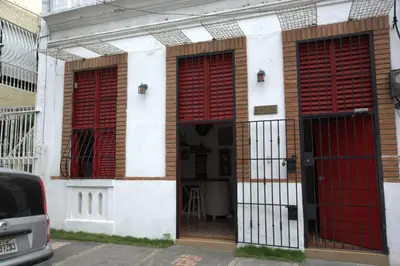 a building with red doors and red shutters on it at La Puerta Roja Guest House in Santo Domingo