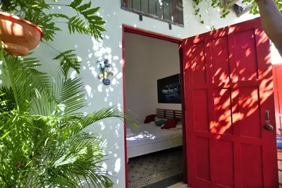 a red door leading to a bedroom with a bed at La Puerta Roja Guest House in Santo Domingo