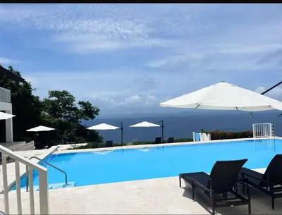 a swimming pool with two chairs and an umbrella at Spectacular Ocean View Top Floor 1-Bedroom Condo, Vista Mare, Samana DR in Santa Bárbara de Samaná