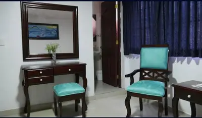a room with a chair and a desk and a mirror at Hotel Luis V Santo Domingo in Santo Domingo