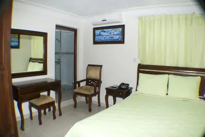 a bedroom with a bed and a desk and a mirror at Hotel Luis V Santo Domingo in Santo Domingo