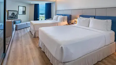 a hotel room with two beds and a couch at Crowne Plaza Santo Domingo by IHG in Santo Domingo